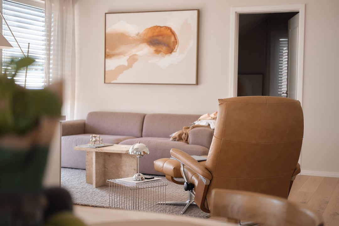 A tan leather recliner and a beige sofa in a sunlit living room