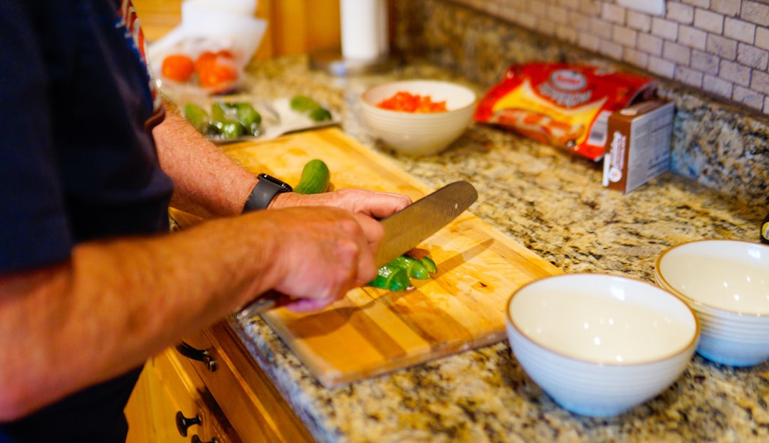 A person chopping green vegetables on a wooden cutting board