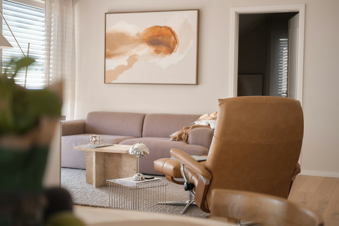 A tan leather recliner and a beige sofa in a sunlit living room